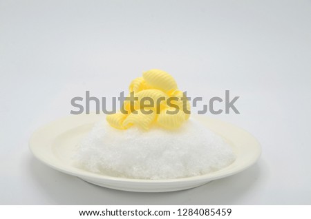 Delicious rolls of butter on a plate with snow. Butter is used for cooking and baking and it adds a tasty flavor to the food. Picture is ideal for advertising dairy products,