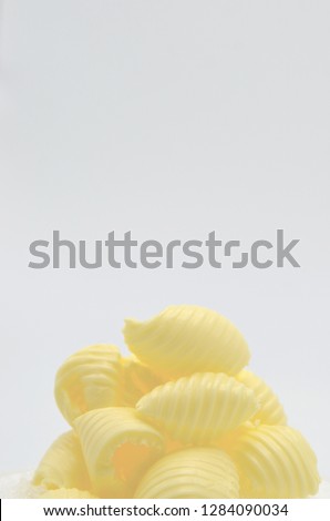 Pile of delicious rolls of butter and a white background. Butter is used for cooking and baking and it adds a tasty flavor to the food. Picture is ideal for advertising dairy products,