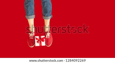 feet with a gift for the holidays on an isolated red background, a girl with a gift, giving gifts, discounts. Lovers day concept,Valentine's Day.