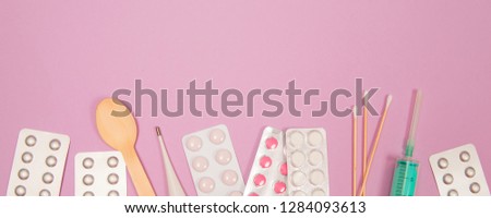Various medicines, thermometer and syringe on pink background with copy space.