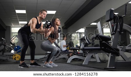 Portrait of two young sportive people doing exercises and training in gym. Beautiful brunette looking away doing sit-ups exercise ang training. Attractive brunet athlete training her.