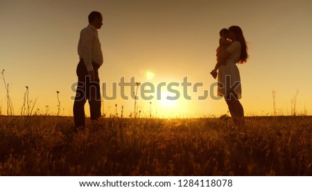 Little daughter goes to her mother in her arms at sunset. Happy mother hugs and kisses baby. Dad, mom and baby are playing for walk in evening. First steps.