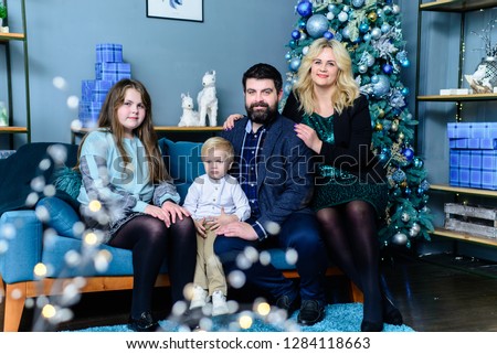 Happy family with children sitting on the sofa in front of the Christmas tree. Family with children posing on the couch, in front of the Christmas tree.