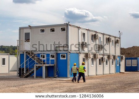 Workers at mobile containers and cabins base for the site manager and employees. Construction site work site fast build mobile prefabricated container houses.
