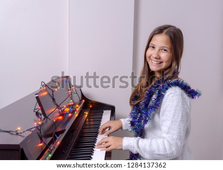 Young girl child plays piano. There are lights on the piano.