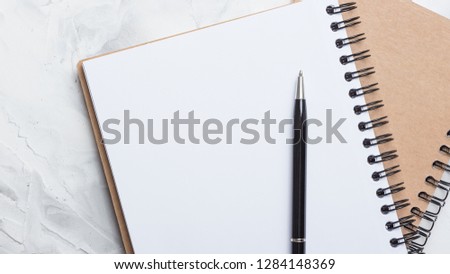 Notebook with pen on light gray desk background with free space.