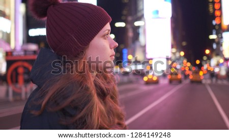 Beautiful girl walks through the city of New York at Times Square by night
