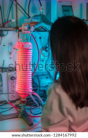 Female scientist working in a biotechnology laboratory with reactors and microalgae cultivation