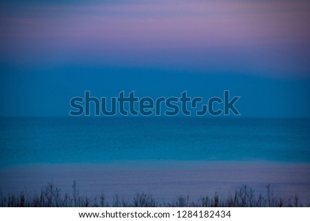  Sea with silver reflection of the sun  with blue sky and clouds in the background