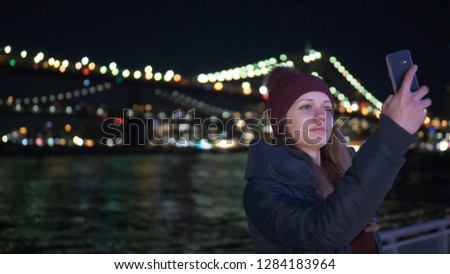 Young woman sits at Brooklyn Bridge New York by night