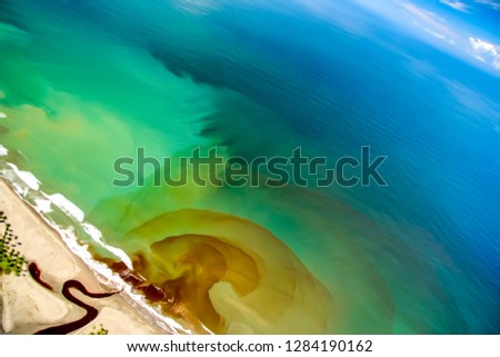 
Tilted high aerial view of a river mouth bringing runoff into the ocean, making many layers of colors in concentric rings. Royalty-Free Stock Photo #1284190162