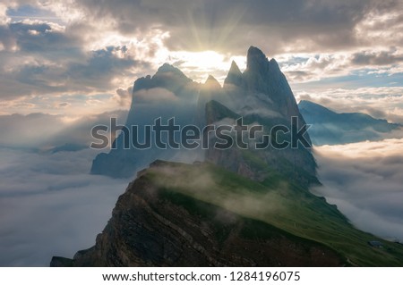 Mountain top peeks above the clouds, illuminated by the sun just after sunrise. Puez Odle-Geisler, Dolomite Alps, Italy. Good image for adventure, motivation and success story photo.