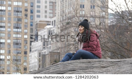 Young woman relaxes on a rock at Central Park New York