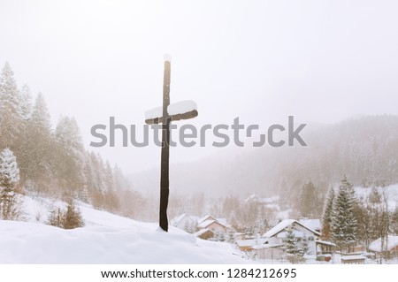 Picture of a cross in the hill of the village in winter sason