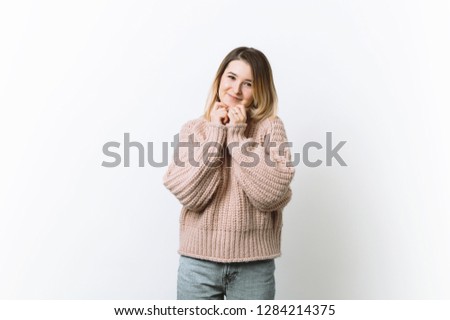 Portrait of slender beautiful  woman in love, holding clasped hands over chest, looking tender pose