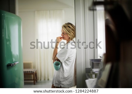 Woman drinking coffee in kitchen.