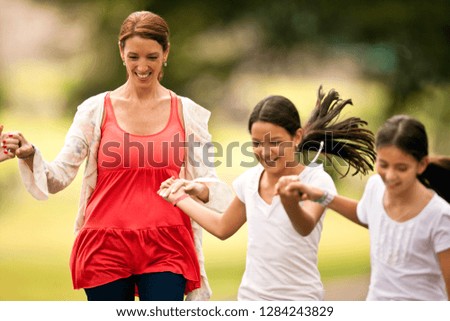 Mature woman having fun walking and holding hands with her daughters.