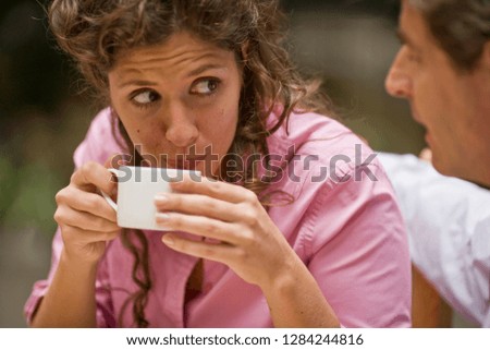 Mid-adult woman drinking a coffee with her husband while sitting at a cafe.