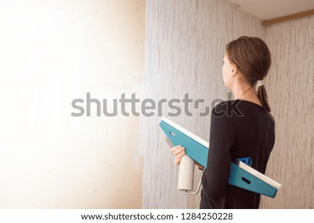 young girl making repairs in the apartment, wallpapering