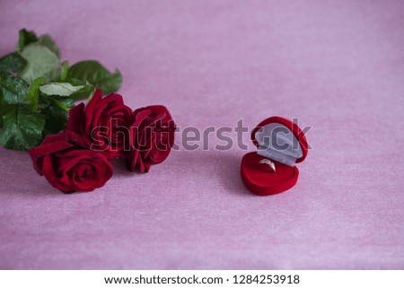 red roses, flowers and gift box for ring (opened) on a pink background, a proposal to get married 