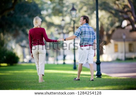 Mid-adult couple taking a romantic walk through a park.