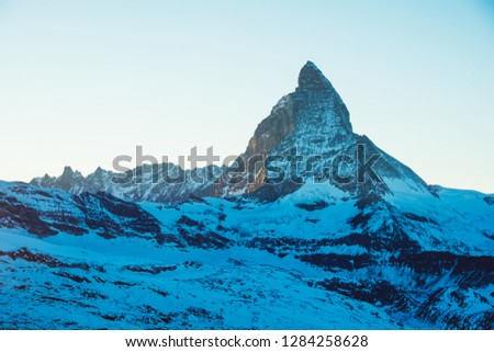 Beautiful nature landscape of Matterhorn mountain peak, Swiss Alps in sunlight rays. Sunset mountains covered with snow in Switzerland. View of Alpine ski resort and sun beams. Winter background.