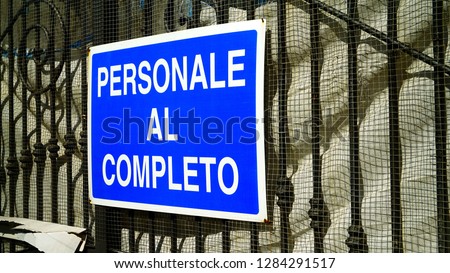 Sign with "complete personal" writing in Italian on the gate of a building site
