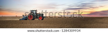 Panoramic landscape view of the tractor on the field sowing. Planting seeds mechanization. Royalty-Free Stock Photo #1284309934