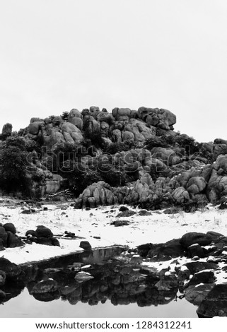 Black and white photo of a snow-covered outcrop of rocks reflected in Watson Lake near Prescott, Arizona. Royalty-Free Stock Photo #1284312241