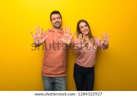 Group of two people on yellow background counting ten with fingers