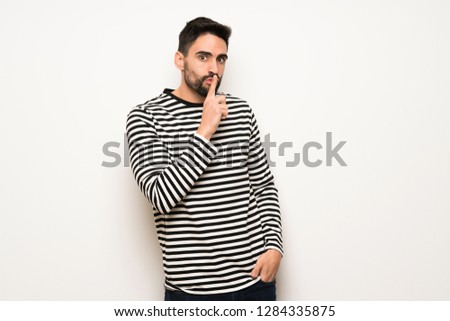 handsome man with striped shirt showing a sign of silence gesture putting finger in mouth