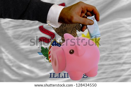 Man putting euro into piggy rich bank and flag of us state of illinois in foreign currency because of insecurity and inflation