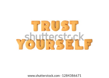 Top view of the word TRUST YOURSELF spelled with alphabet shaped biscuits isolated on white background
