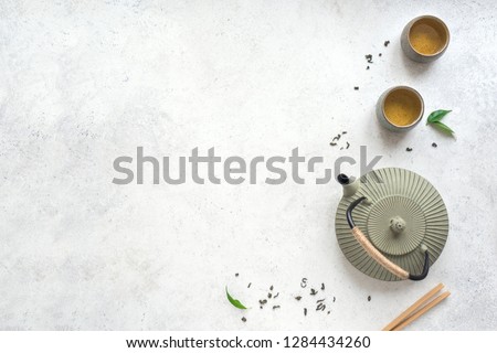 Green Tea Set -  iron teapot and ceramic teacups with green tea and leaves. Traditional asian tea composition on white background, copy space, top view. Royalty-Free Stock Photo #1284434260