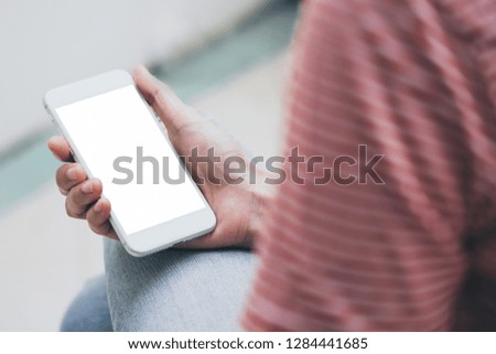 mockup image of woman's hand holding texting white cell phone at outdoor with copy space,blank screen for text.concept for business,people communication,technology electronic device.modern life style