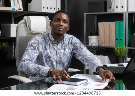 Portrait of Beautiful young African American businessman working with documents and laptop in office