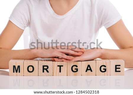 cropped view of woman with hands on wooden cubes with mortgage lettering isolated on white