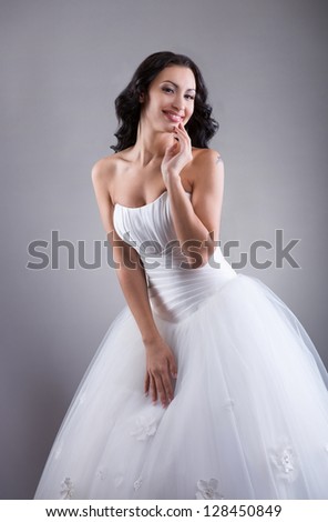 Smiling beautiful bride posing for photo, indoors, grey background