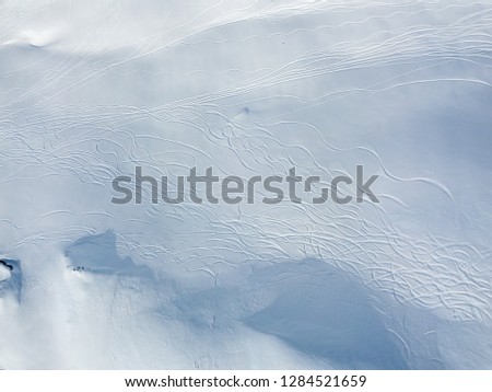 Aerial view of ski tracks in snow. Backcountry skiing in powder, leaving trails in snow.