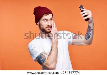  A young man takes pictures of himself on the camera in the phone.                              