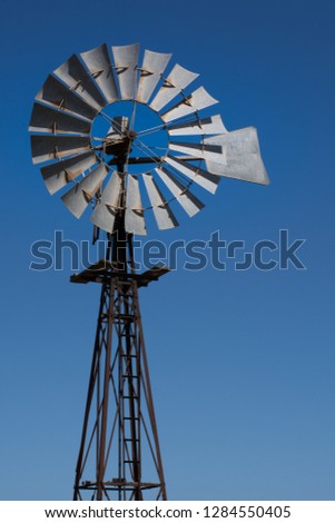 Australian Windmill head detail, isolated against blue sky, used to pump water for stock and crops, outback South Australia, portrait orientation, room for text.