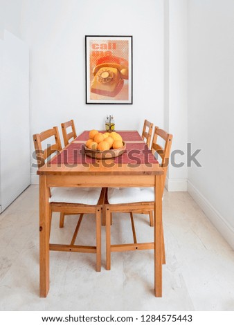 Cozy wooden table and chairs, picture frame in a spacious modern kitchen.