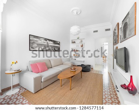 Confortable stylish bright living room with natural ratan carpet, sofa, wooden table, pictures and plants. Spacious modern interior in earthy colors