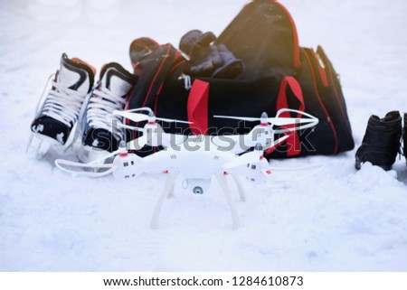 the drone for flights costs on snow with winter skates and a bag, a theme of active recreation and technologies