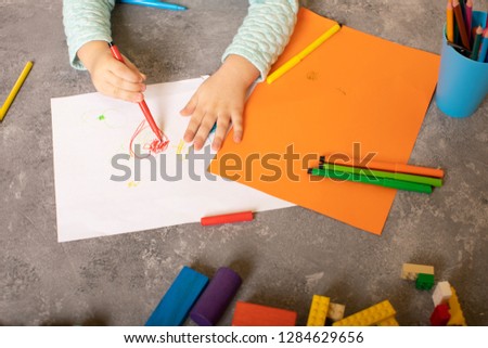 Little Child enthusiastically Draws with Pencils and felt-tip pens on colored paper and makes crafts with his hands. Kid Plays in the kids club for development and creativity. Playroom for children  