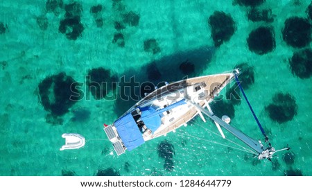 Aerial drone bird's eye view photo of sail boat docked in tropical caribbean paradise bay with white rock caves and turquoise clear sea