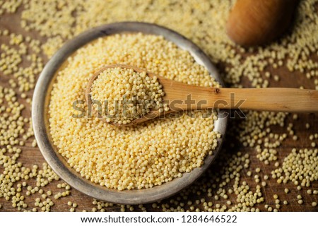 Millet in spoon above bowl, top view  Royalty-Free Stock Photo #1284646522