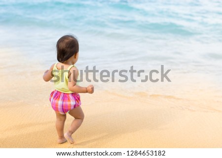 Cute baby girl walking on the beach. 