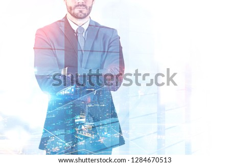Unrecognizable bearded businessman in dark suit standing with crossed arms with double exposure of night cityscape. Toned image mock up