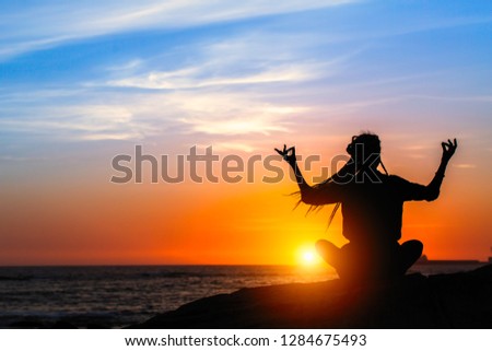 Yoga meditation woman on the ocean during amazing sunset. 